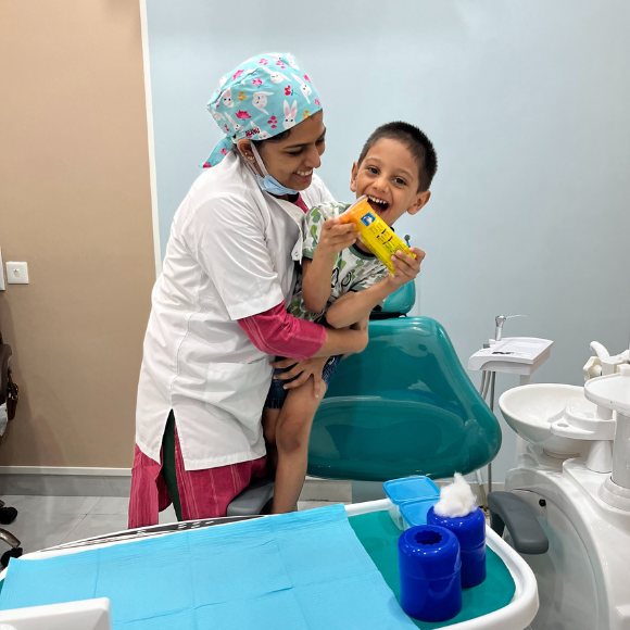 a happy child is excited on receiving a gift from Dr Anushree after dental treatment